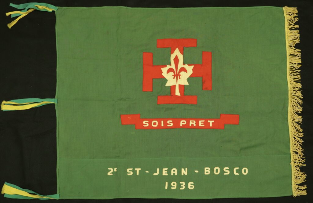 Green flag with red and white Scouts logo, the slogan "Sois Pret" and the group name "2e St-Jean-Bosco 1936"